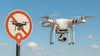 DJI Phantom drone flying in sky with a sign behind it showing a no fly zone symbol on it