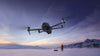 DJI Mavic 4 Pro drone flying in snowy landscape with a person standing in the background