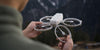 Person unfolding DJI Neo drone with mountainous background