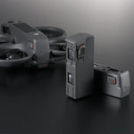 Two drone batteries on a dark surface with a blurred Avata 2 drone in the background