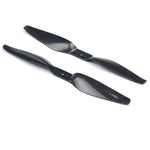 Two black carbon fiber propellers, one with a clockwise rotation and the other with a counter-clockwise rotation, against a white background