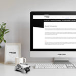 Computer monitor displaying the online training portal, on a desk with a drone, mug, plant and photo frame.