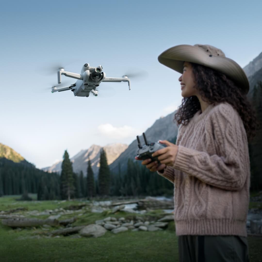 A woman flying a drone in a mountainous landscape