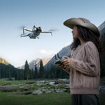 A woman flying a drone in a mountainous landscape