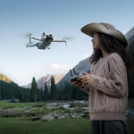 A woman flying a drone in a mountainous landscape