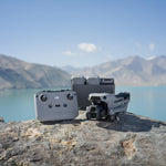 DJI Air 3S drone, RC-N3 controller and three drone batteries on a rock with a mountainous landscape in the background