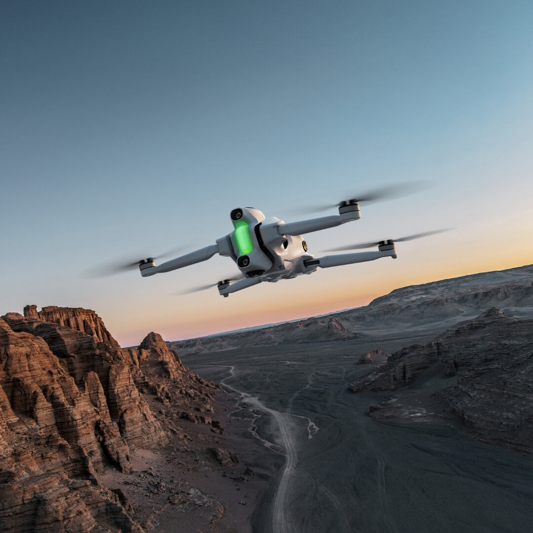 Unmanned aerial drone flying over a desert landscape with a sunset