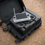 Enterprise drone controller on top of an open black battery station case on a sandy surface