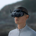A man wearing the dji fpv goggles 3 with a mountainous background