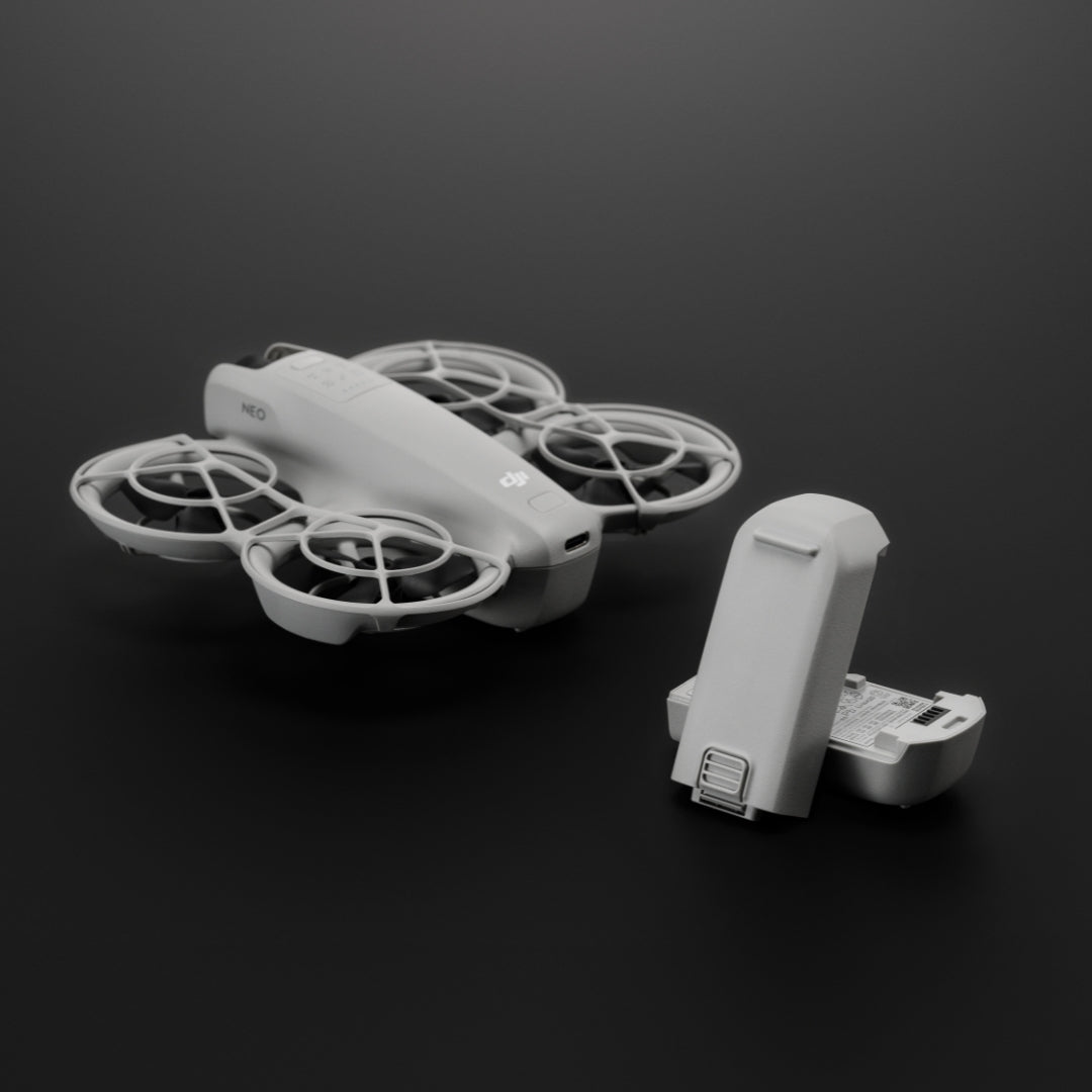 Two white batteries and DJI Neo drone on a dark background