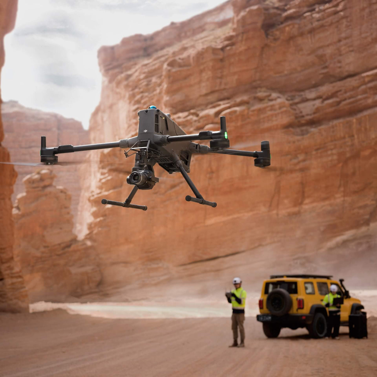 Large Matrice 400 enterprise drone flying over a desert landscape with a person and vehicle in the foreground