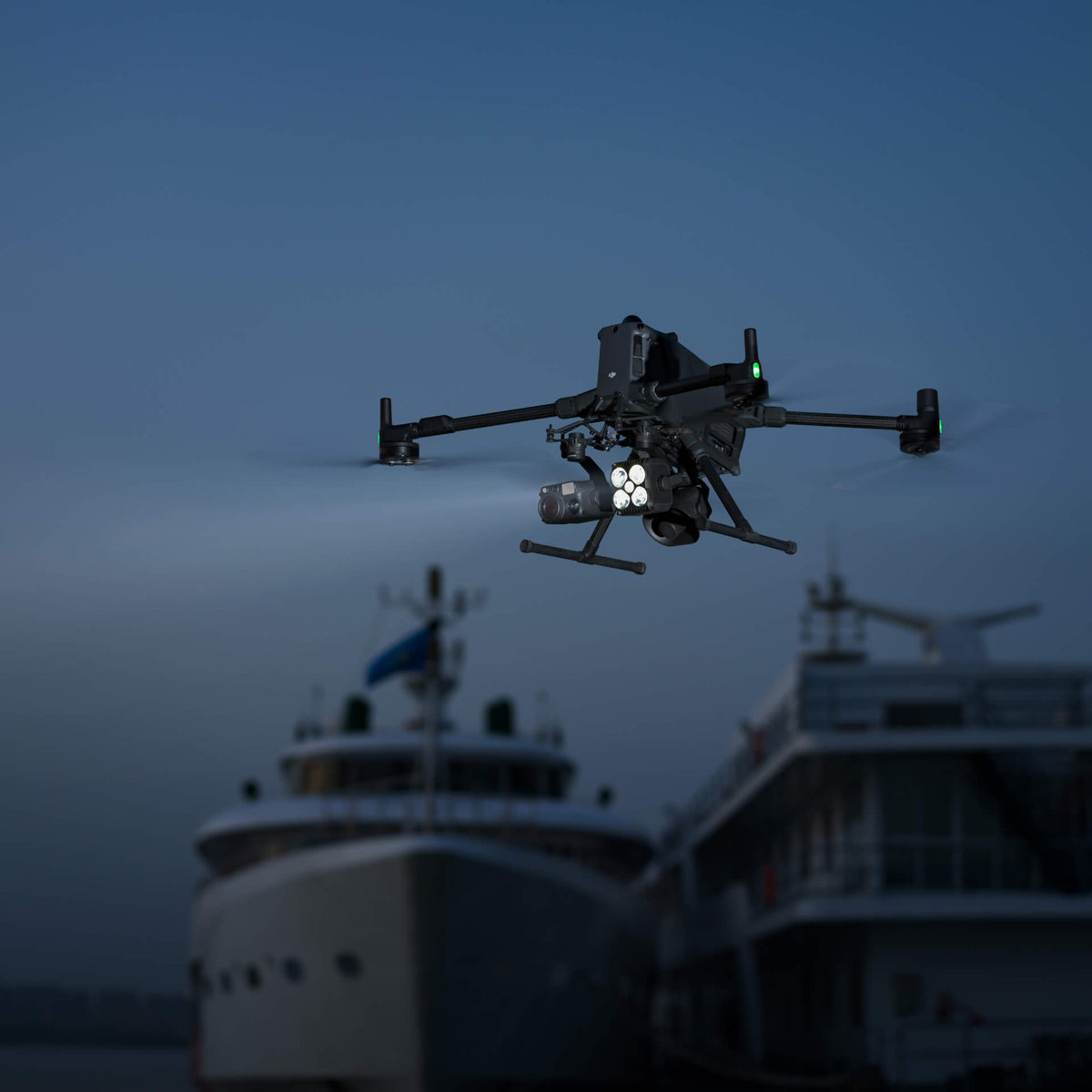 Large Matrice 400 enterprise drone flying over a harbour at night with boats in the background