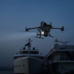 Large Matrice 400 enterprise drone flying over a harbour at night with boats in the background