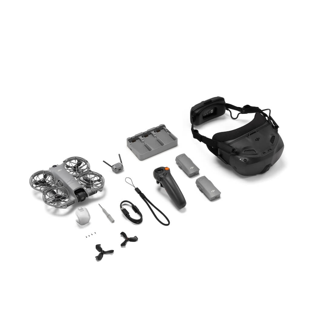 Collection of drone components including a helmet, drone, remote control, and accessories on a white background.