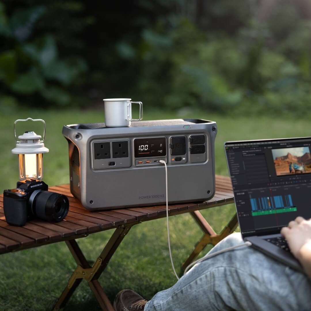 Portable Power 1000 V2 station with a laptop, camera and lantern on a table outdoors