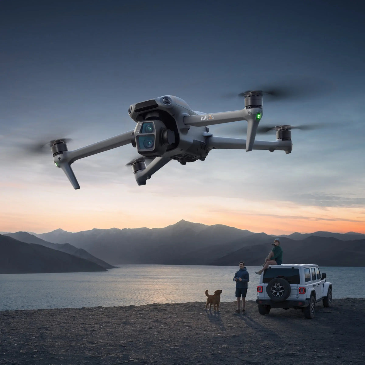 DJI Air 3S drone flying over a scenic landscape with mountains and a lake at sunset