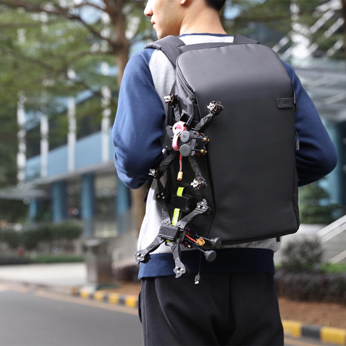 Person wearing a black backpack with visible electronic components outdoors