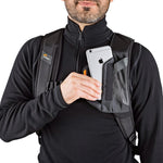Person placing smartphone into black backpack strap on a white background