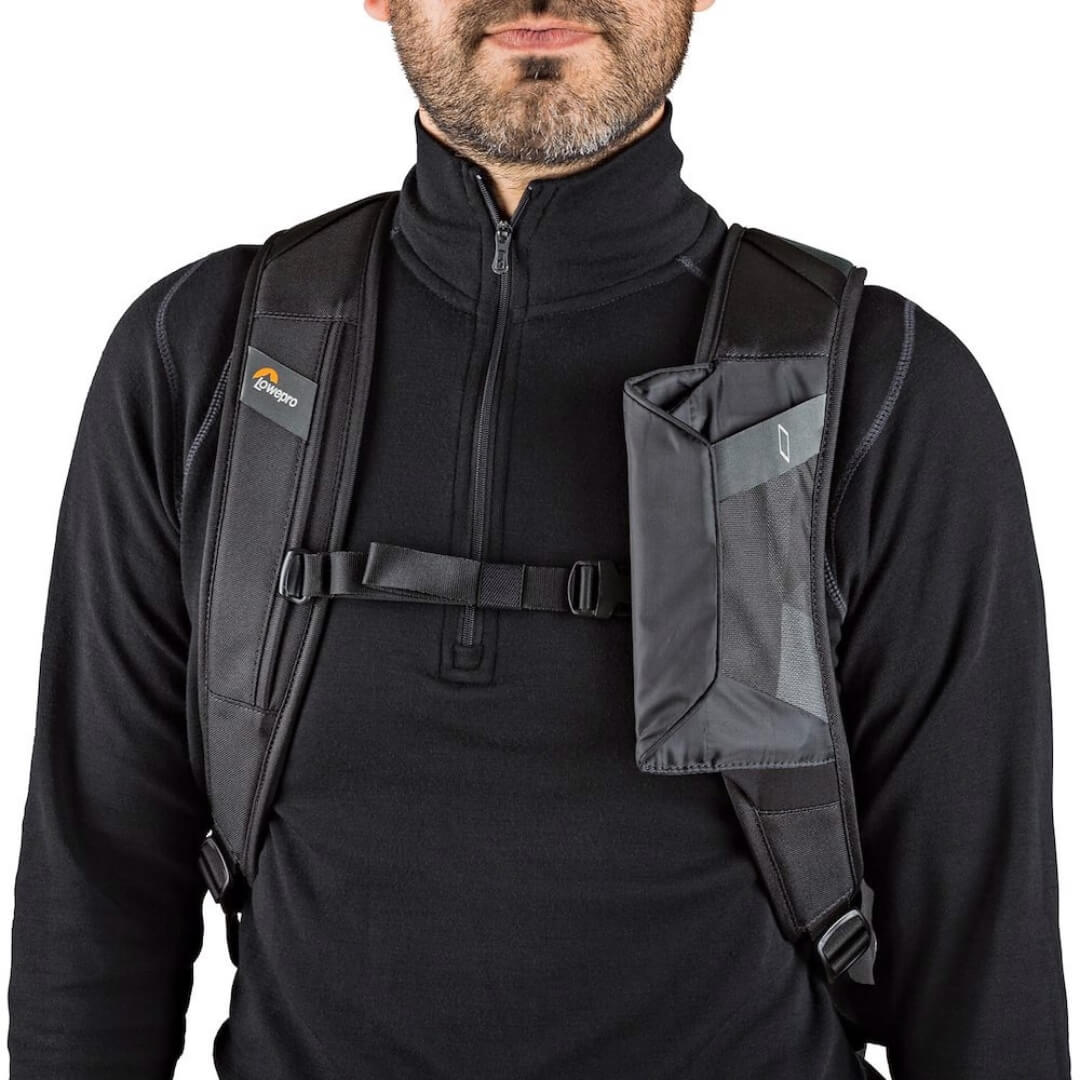 Person wearing a black backpack with visible brand logo on right strap against a white background
