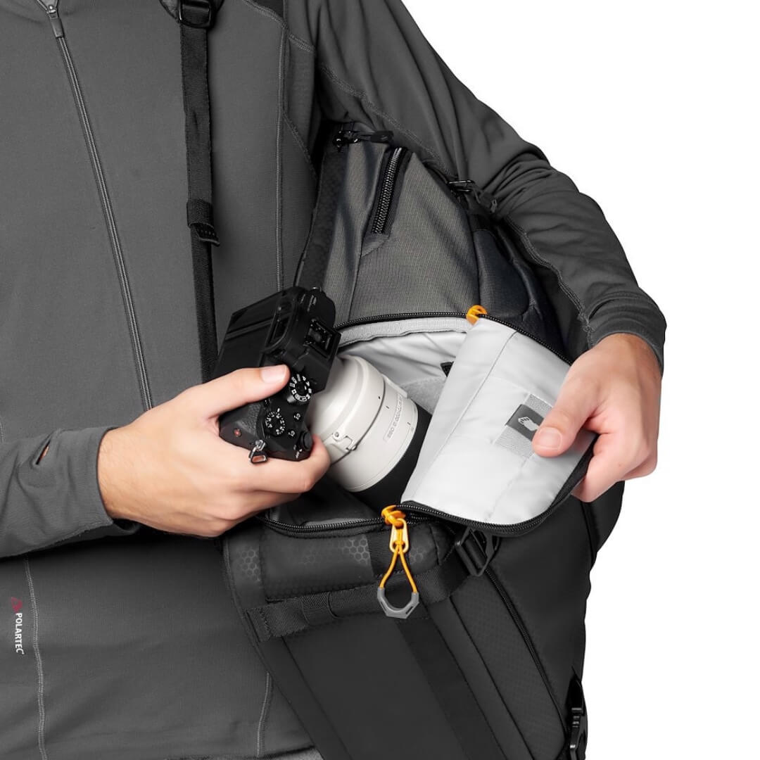 Person accessing a backpack with a camera and other items inside