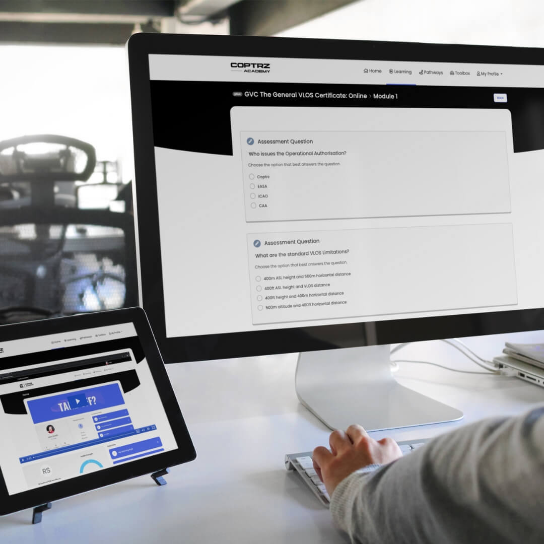 Person using a computer with multiple screens displaying different training portal interfaces on a desk