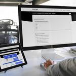 Person using a computer with multiple screens displaying different training portal interfaces on a desk