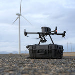 Drone on a carrying case with wind turbines in the background