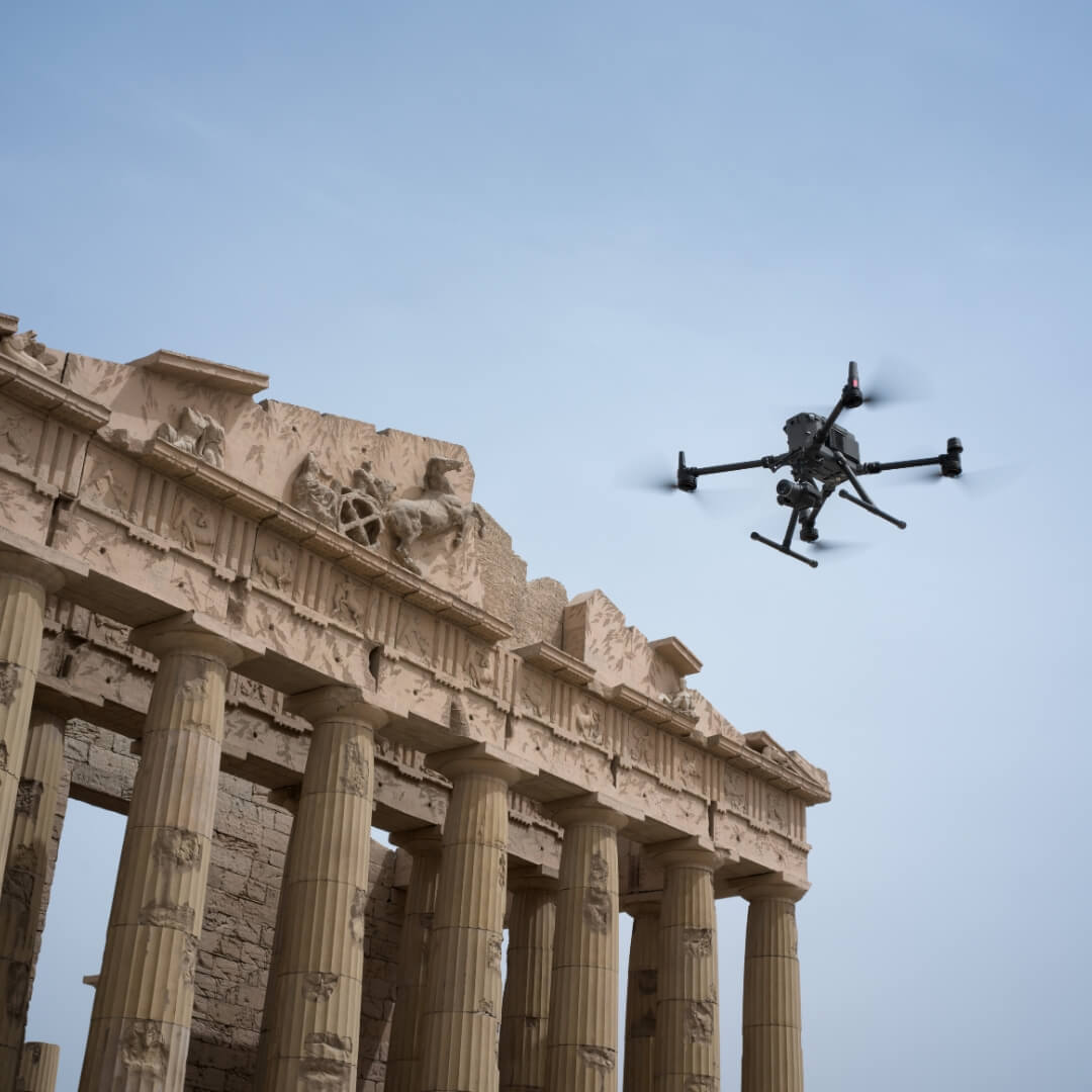 Drone flying over ancient stone architecture with a clear blue sky