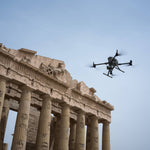 Drone flying over ancient stone architecture with a clear blue sky