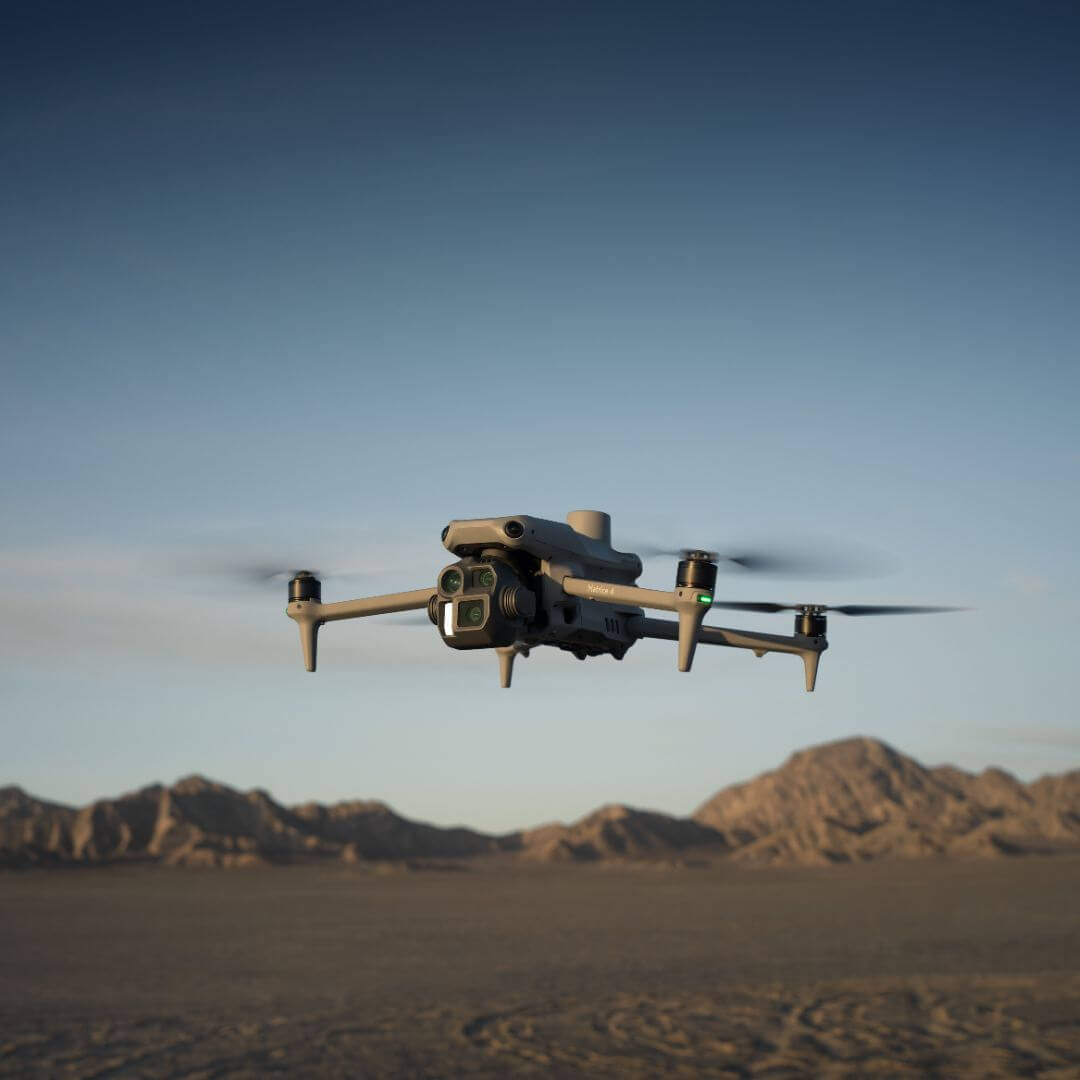 DJI Matrice 4E drone flying over a desert landscape with mountains in the background