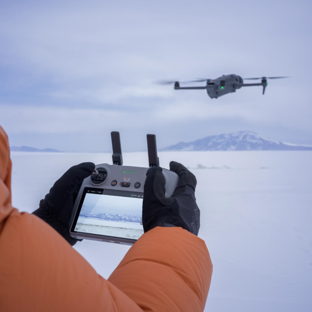 Person operating a drone with a controller in a snowy landscape