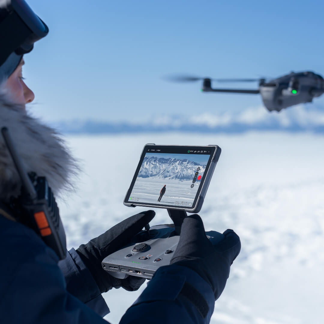 Person operating Mavic 4 Pro drone using RC Pro 2 remote controller with a snowy landscape