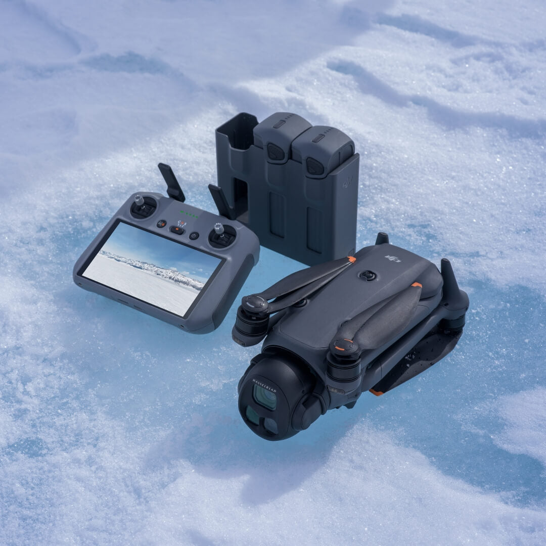 Mavic 4 Pro drone, remote controller and charging hub with 2 inserted batteries on a snowy surface