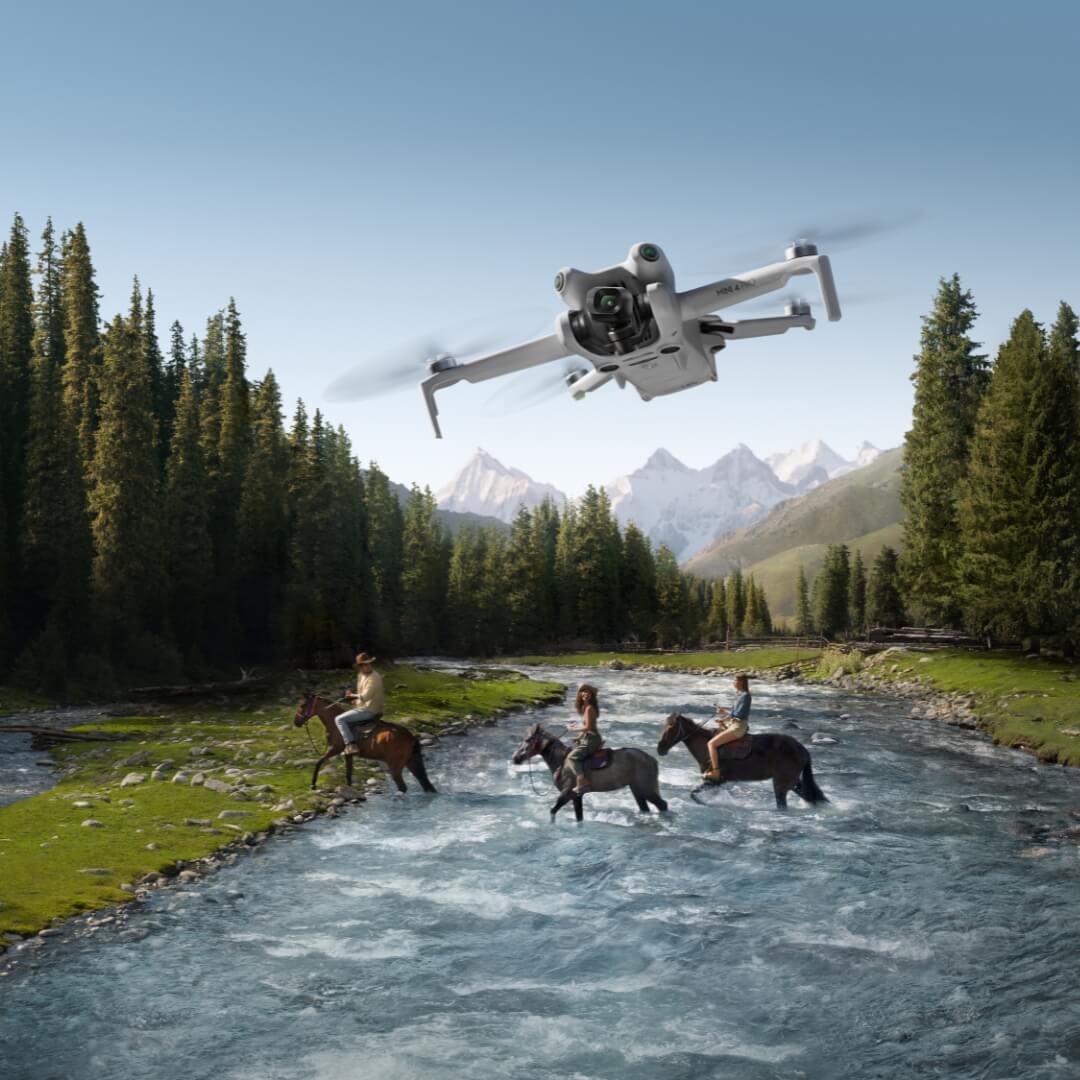 Mini 4 Pro drone flying over a scenic landscape with people on horses crossing a river