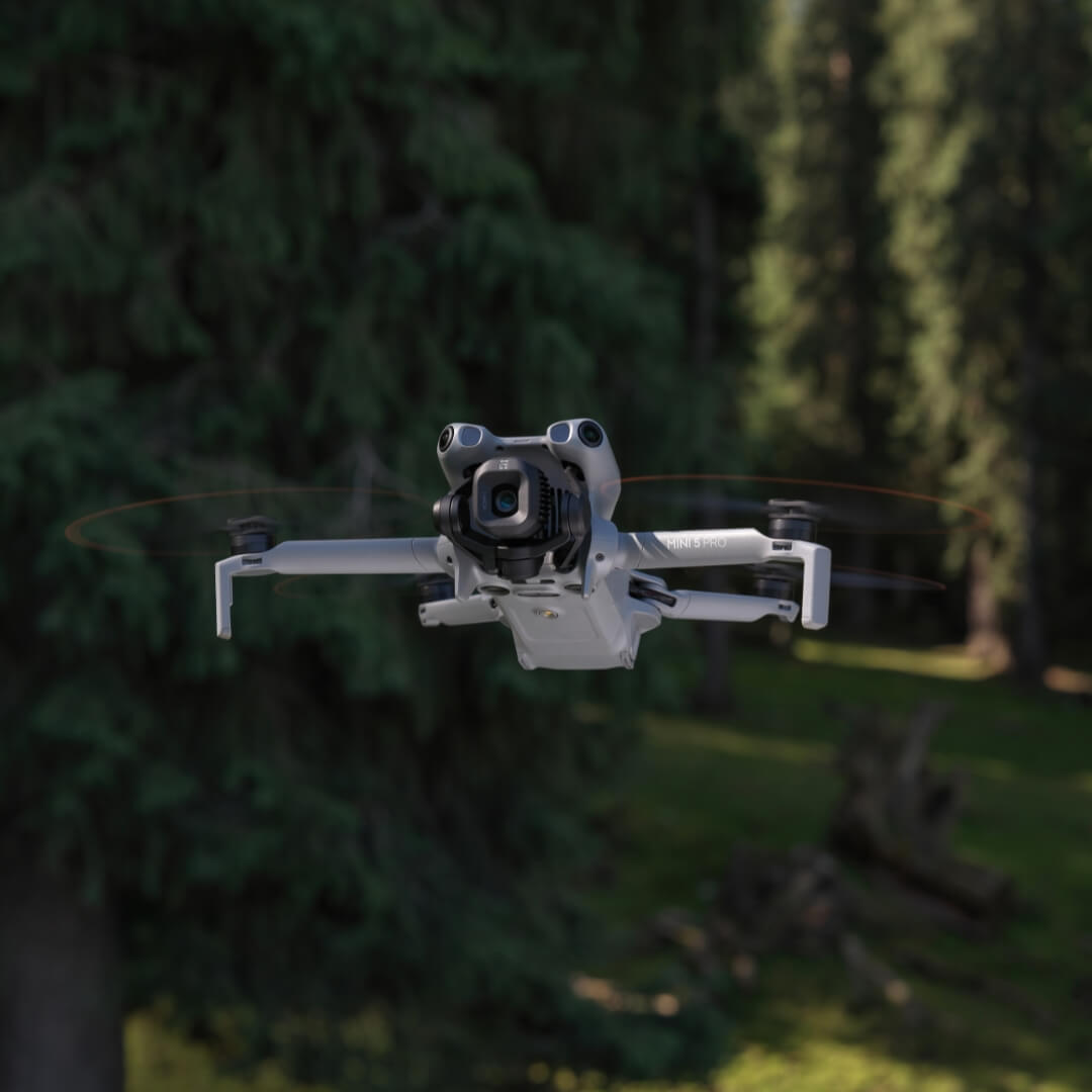 Mini 5 Pro grey drone flying over a forested area