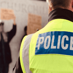 Man wearing yellow high-visibility jacket with Police written on the back