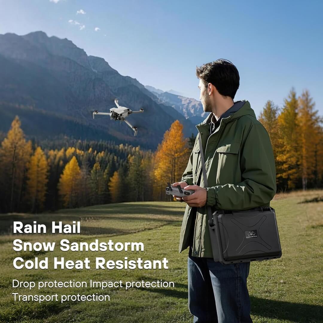 Man operating a drone in a scenic outdoor setting with mountains and trees.