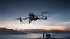 DJI Air 3S drone flying with sunset lake setting and mountains in the background