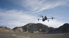 DJI Matrice grey drone flying towards a mountain within the desert