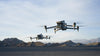 Two DJI Matrice drones flying in the sky with desert-like mountainous background