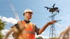 A man holds his palm below a grey enterprise drone with a sunny blue sky in the background