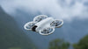 DJI Neo grey drone flying with mountainous background
