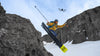 Snowboarder doing a trick on snowy mountain with drone flying above them