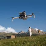Mini 5 Pro drone flying over a scenic landscape with mountains and a woman in a white dress