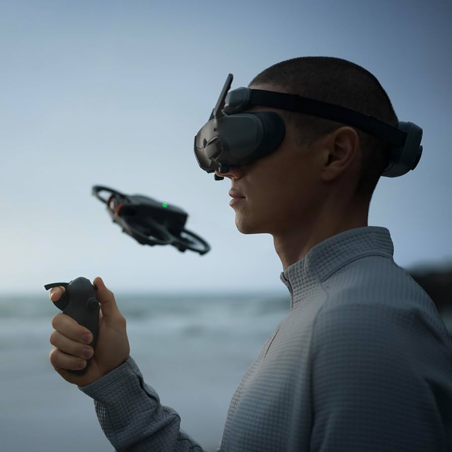 A man wearing the dji fpv goggles 3 and holding a controller with a drone flying in the background