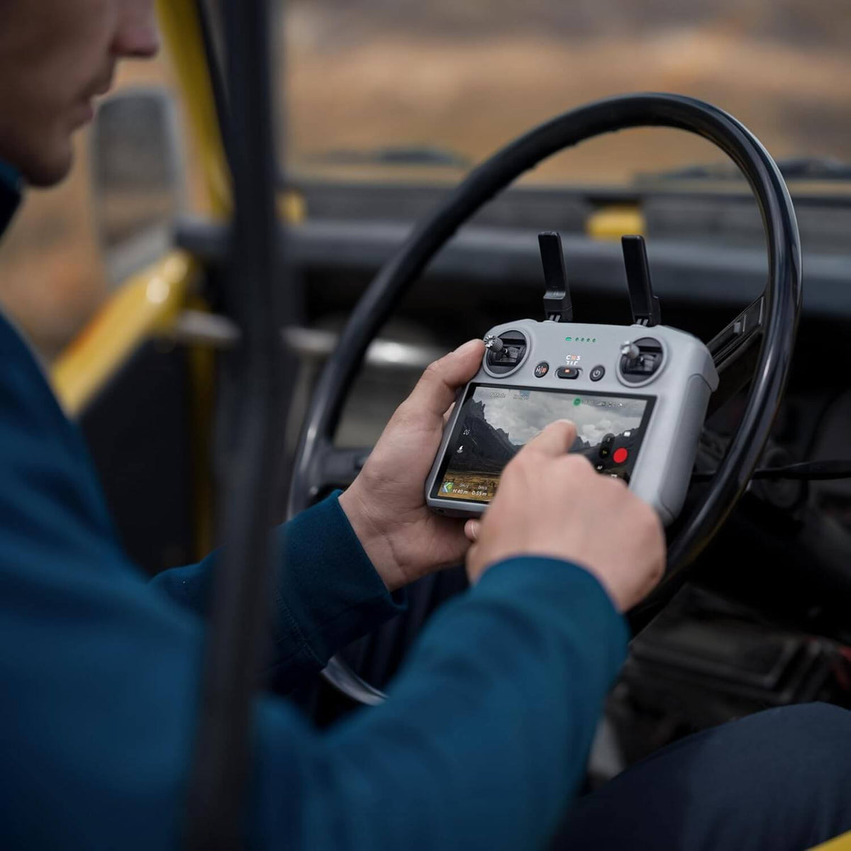 Person operating a drone with a remote control inside a vehicle
