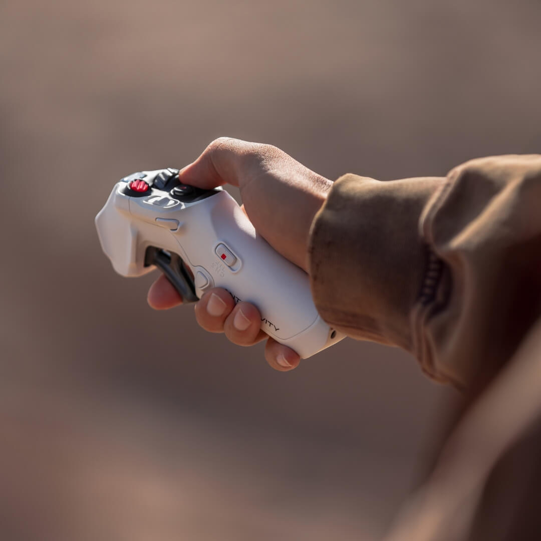 Hand holding a white drone controller against a blurred background