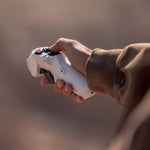 Hand holding a white drone controller against a blurred background