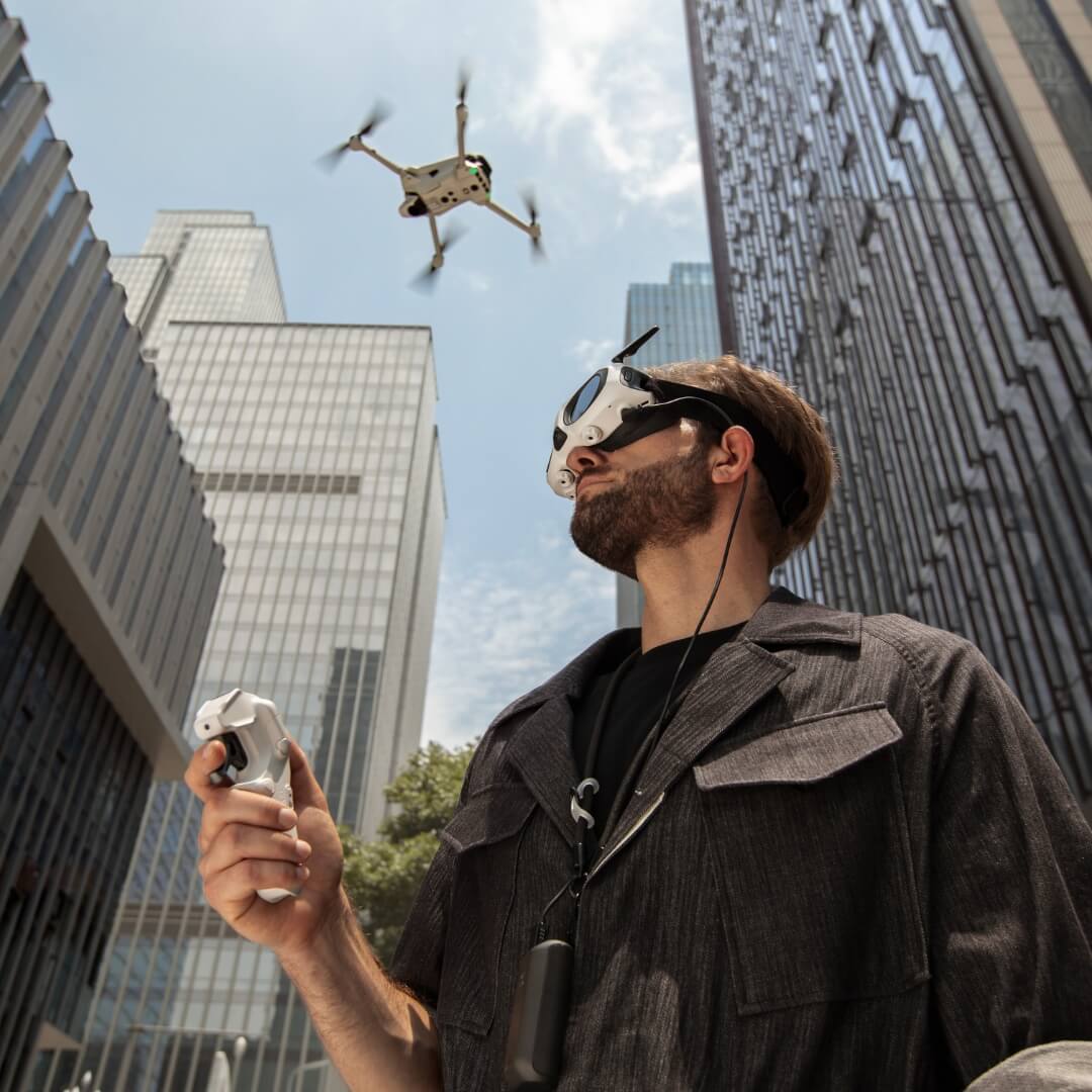 Man operating an Antigravity A1 drone in an urban setting with tall buildings