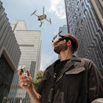 Man operating an Antigravity A1 drone in an urban setting with tall buildings